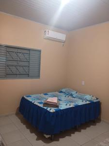 1 dormitorio con 1 cama con manta azul y aire acondicionado en Hotel - Pousada e Restaurante Dona Benta, en Novo Acordo