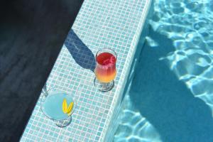 a drink in a glass next to a swimming pool at Banja na Drini - Lux vikendice, apartmani, na obali reke in Banja Koviljača