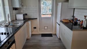 a kitchen with a sink and a refrigerator at Cosy Bournemouth Bungalow in Longham +25 photos