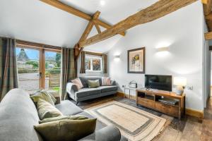 a living room with a couch and a tv at Long Barn in Little Marcle