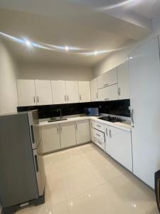 a white kitchen with white cabinets and a refrigerator at Full Furnished House Entire Place No Sharing in Rāmkot