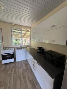 a kitchen with white cabinets and a black counter top at Fare chez Franck in Tevaitoa