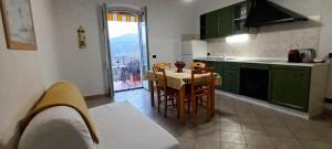 a kitchen with green cabinets and a table and chairs at Casa Arcobaleno apartments-Room holiday home in Diano dʼAlba