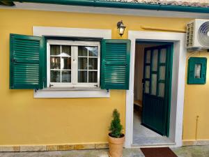 a yellow house with green shutters and a window at Nennella's House in Ágios Rókkos
