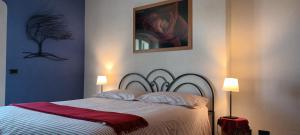 a bed in a bedroom with two lamps and a painting at Casa Arcobaleno Holiday home apartments in Diano dʼAlba