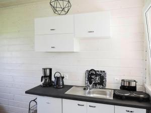 eine Küchentheke mit weißen Schränken und einer Spüle in der Unterkunft Bungalow in Kolczewo near Baltic Sea Beach in Kołczewo + 16 Fotos