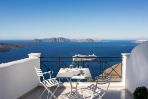 a white table and chairs on a balcony with the ocean at Villa Renos Hotel in Fira
