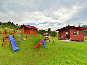 a group of playground equipment in a field with a house at Cottage in Rusinowo near Seaside Beach in Rusinowo