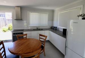 a kitchen with a wooden table and a refrigerator at 36 Betka Road in Mallacoota