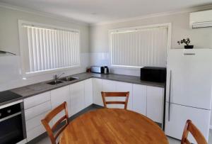 a kitchen with a table and a white refrigerator at 36 Betka Road in Mallacoota