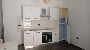 a white kitchen with a stove and a refrigerator at House in Sardegna in Triei