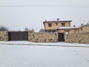 a snow covered street with a stone fence and a house at Las Damas casa rural in Avila