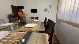 a dining room with a long table with chairs and a television at Casa de Temporada Umuarama in Uberlândia