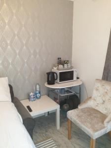 a small living room with a microwave and a couch at Room Stay - Marks tey, Colchester, United Kingdom in Marks Tey +12 photos