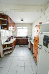 a kitchen with a refrigerator and a white tiled floor at Pousada Espaço Viagi in Taubaté