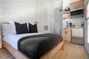 a bedroom with a large bed and a kitchen at Studio #1 - Self Check-In - Plateau - St-Denis in Montreal