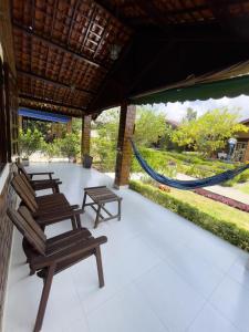 a porch with chairs and a hammock in a resort at Aconchego em Gravatá! Temporada in Gravatá