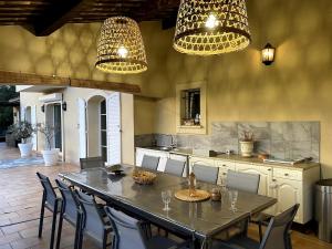 una cucina con tavolo, sedie e lampadari a braccio di Bastide à Trans en Provence avec piscine et vue sur le massif des Maures a Trans-en-Provence
