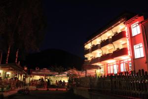 ein beleuchtetes Gebäude mit Menschen, die nachts draußen sitzen in der Unterkunft Yagodina Family Hotel in Yagodina