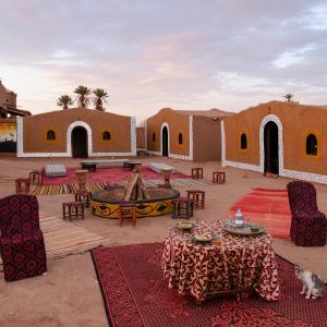 un accampamento nel deserto con tavoli, sedie e edifici di Nomads Heaven Camp a M'Hamid