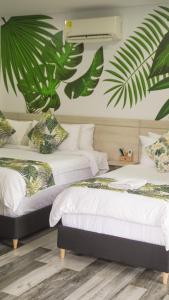 two beds in a room with palm leaves on the wall at Hotel Wayra Club in Acacías
