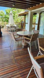 a deck with tables and chairs and a table and a umbrella at Casa em Praia do Forte Refúgio Luxo e Natureza in Praia do Forte