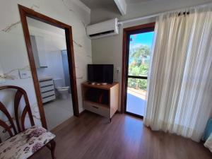 a room with a television and a door to a bathroom at Pousada Recanto Barão de Biguaçu in Biguaçu