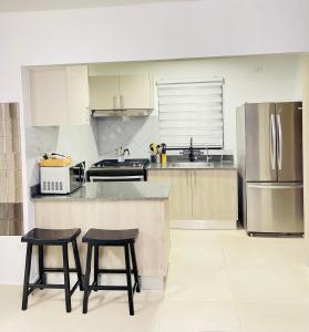 Una cocina con dos taburetes y un mostrador y un refrigerador. en Downtown Punta Cana luxuryVilla, en Punta Cana