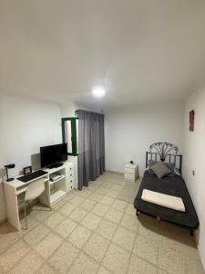 Un dormitorio con una cama, un escritorio y un televisor. en Casa Tamarán, en Arguineguín