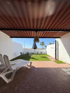Un patio con una silla y una mesa y un techo. en Casa Tamarán, en Arguineguín