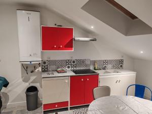a kitchen with red and white cabinets and a table at Les 3 Frontières Luxembourg Grand Parking Wifi in Herserange