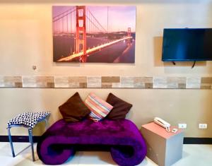 un canapé violet avec une photo du pont de la porte dorée dans l'établissement BGC Mckinley City Center Apartments - Global City, à Manille