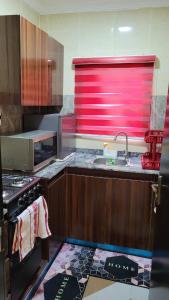 a kitchen with a sink and a red window in it at stay at Creo's one bedroom swimming pool and gym in Ibeju