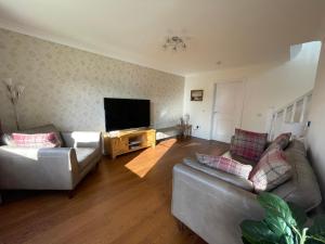 a living room with two couches and a flat screen tv at Inverness Retreat in Inverness