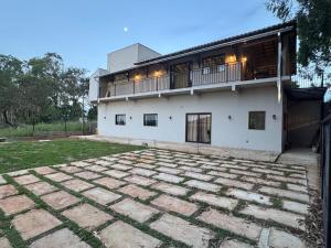 ein weißes Haus mit einer großen Steinterrasse in der Unterkunft Hospedagem Café São Thomé in São Thomé das Letras
