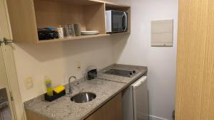 a small kitchen with a sink and a microwave at Flat MERCURE Premiu Executive in Manaus