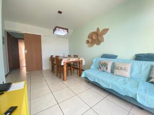 a living room with a blue couch and a table at Movida Cabo Frio in Cabo Frio