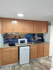a kitchen with wooden cabinets and a microwave at Casinhas da aldeia-casa da xiquita in Seia
