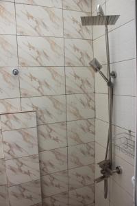 La salle de bains est pourvue d'une douche et d'un mur en marbre. dans l'établissement Green House, 1bdr Apt, 7 min from Airport, à Accra 7 autres photos