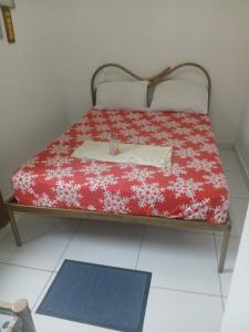 a bed in a room with a red blanket with a table at Alugyel 1 quarto,Aconchegante, ar de nostalgia in Fortaleza