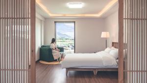 a woman sitting in a green chair in a bedroom at Sorok Stay Gamseung Sookso in Gyeongju +17 photos