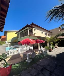 a house with red umbrellas and tables and chairs at Casa Entre o Mar e a Lagoa in Saquarema