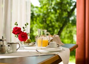 a table with a glass pitcher of orange juice and roses at Studio in Bad Füssing - Bayern 53139 in Bad Füssing