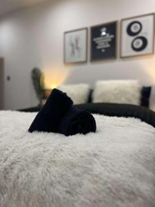 a black towel laying on top of a white bed at Wild Central Suite - Ping Pong Table, Free Gym in Leicester