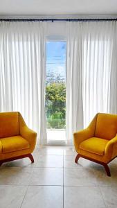 two orange chairs in a room with a window at Ocean Breeze Apartment in Puerto Baquerizo Moreno