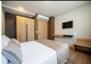 una camera da letto con un letto bianco e una televisione di Laguetto Bianca a Gramado