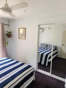 a bedroom with two beds and a mirror at Bushland View Retreat in Ocean Shores