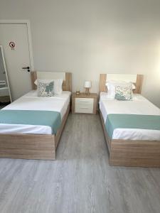 ein Schlafzimmer mit 2 Betten und einem Tisch mit einem Nachttisch in der Unterkunft Maré Alta - Deluxe Stay Minutes To Marina Center in Vila Franca do Campo + 14 Fotos