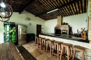 a kitchen with a bar with a fireplace and a refrigerator at Casa Rio Doce in Natal