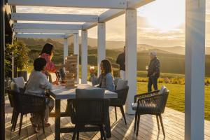 a group of people sitting around a table on a deck at Te Karaka Lodge in Port Waikato